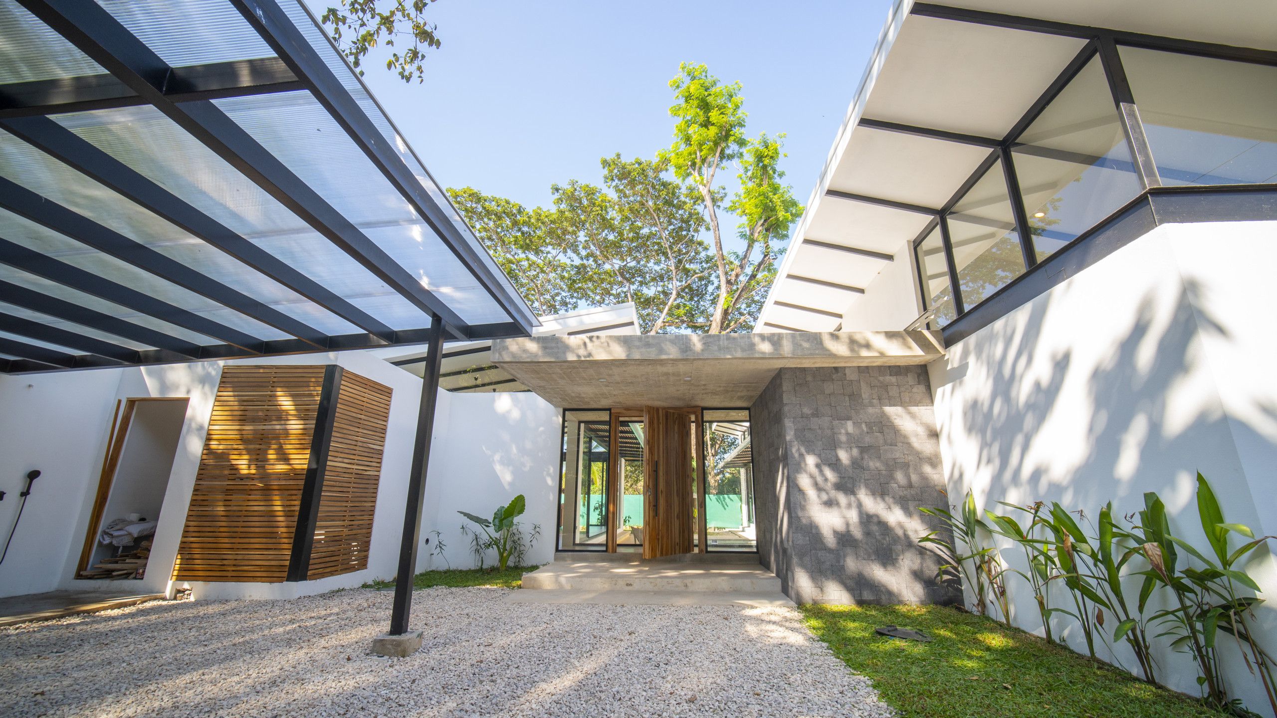 A modern building with a covered patio area, a concrete structure, and a gravel ground.