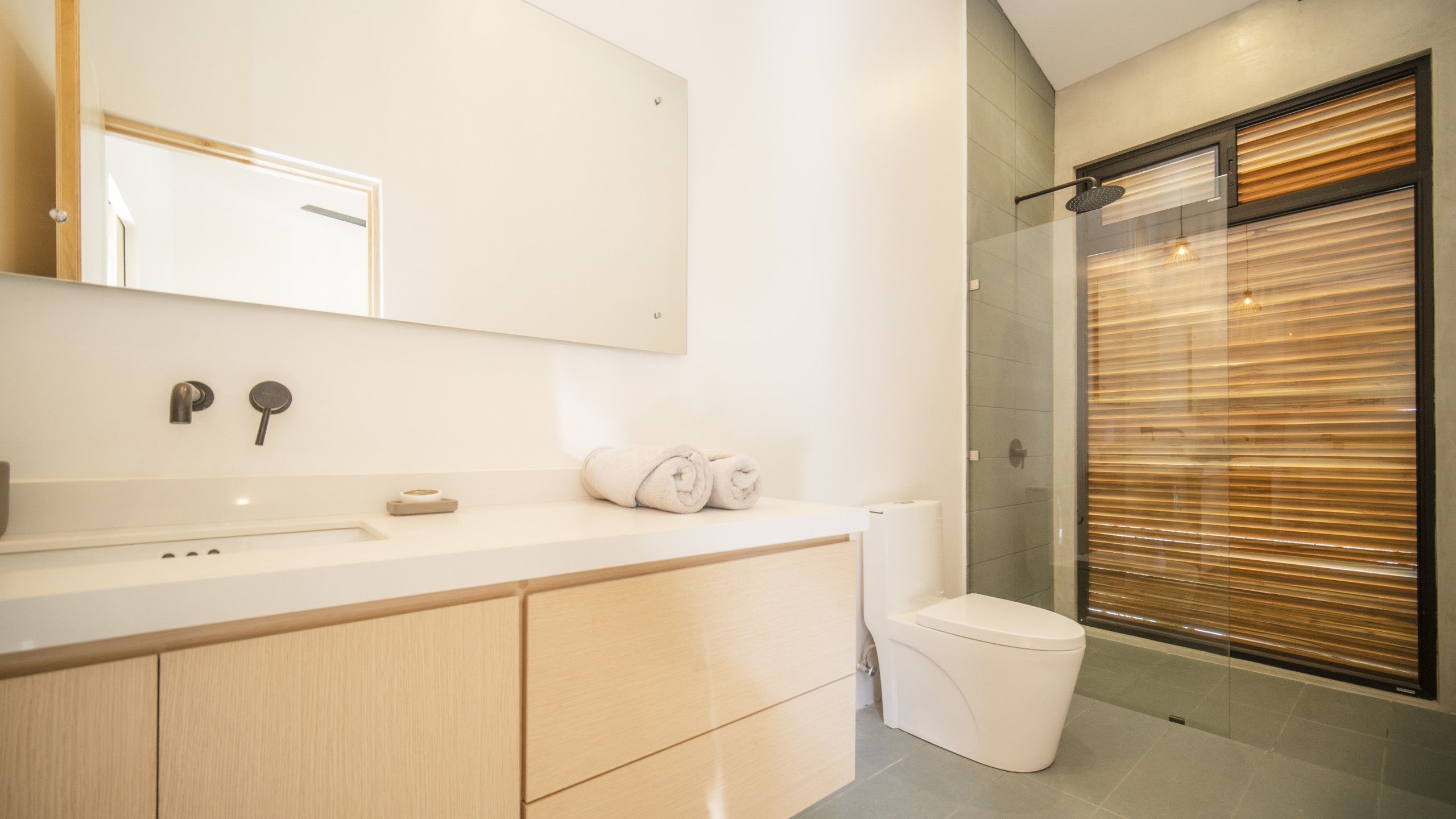 A modern bathroom with a glass shower enclosure, a white sink, and a wooden vanity.