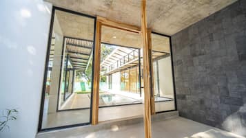 Un intérieur moderne avec de grandes portes vitrées donnant sur un espace extérieur, un plafond en béton et un mur en pierre.