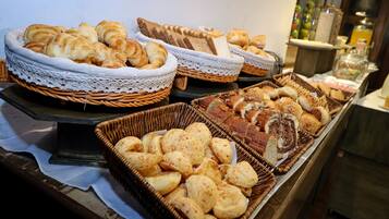 A buffet with various breads and pastries.