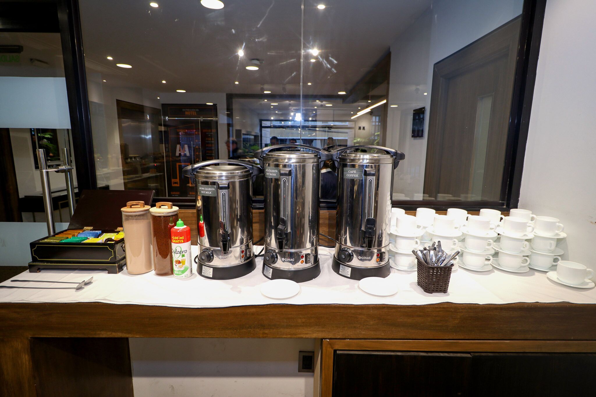 A buffet setup with coffee makers, cups, and condiments.
