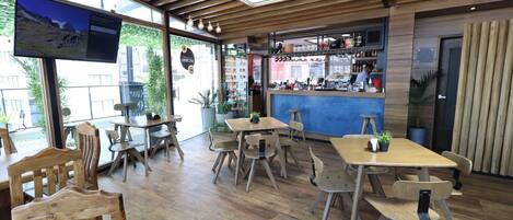 A restaurant with wooden furniture, a bar area, and large windows.