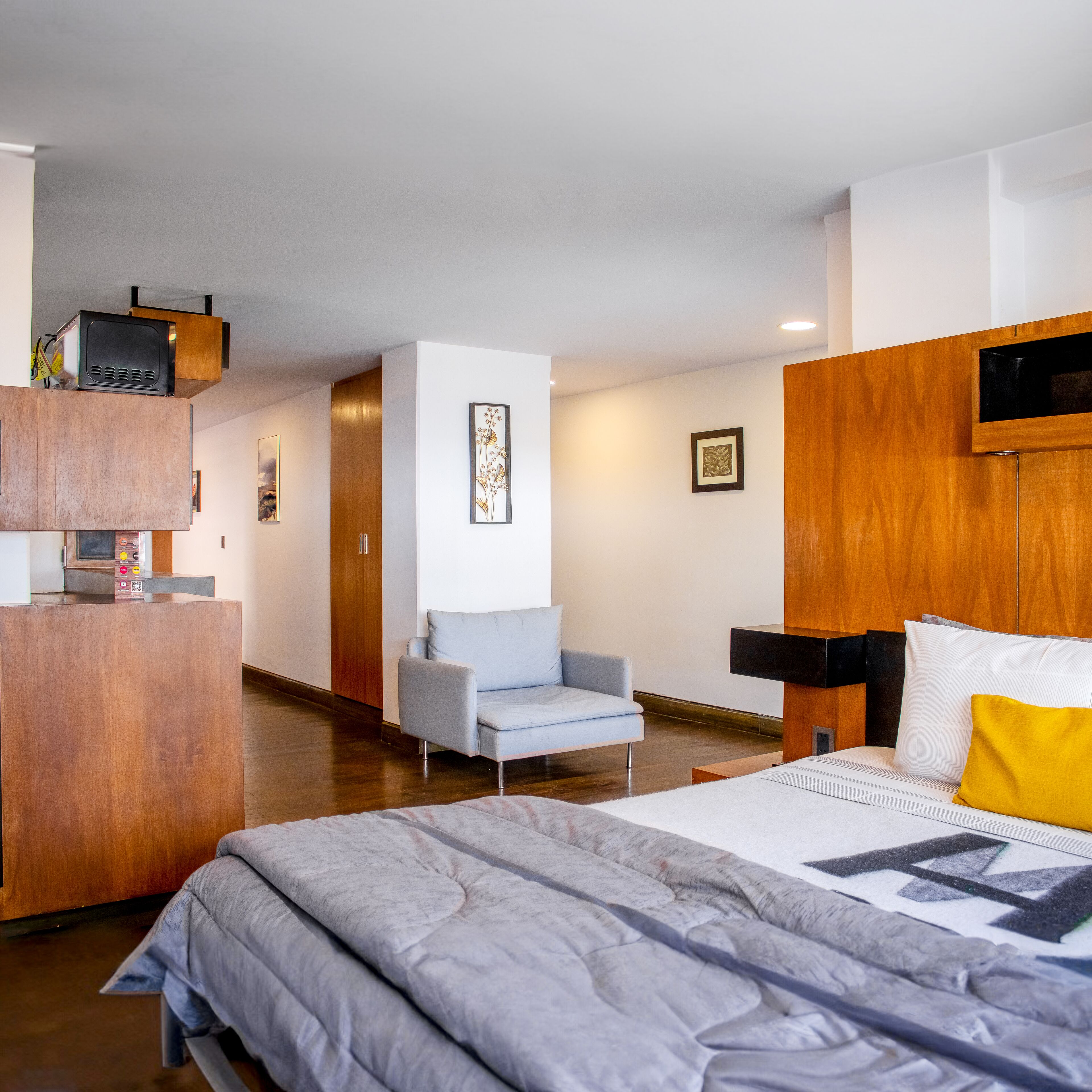 A modern hotel room with a bed, a sofa, a desk, and a TV.