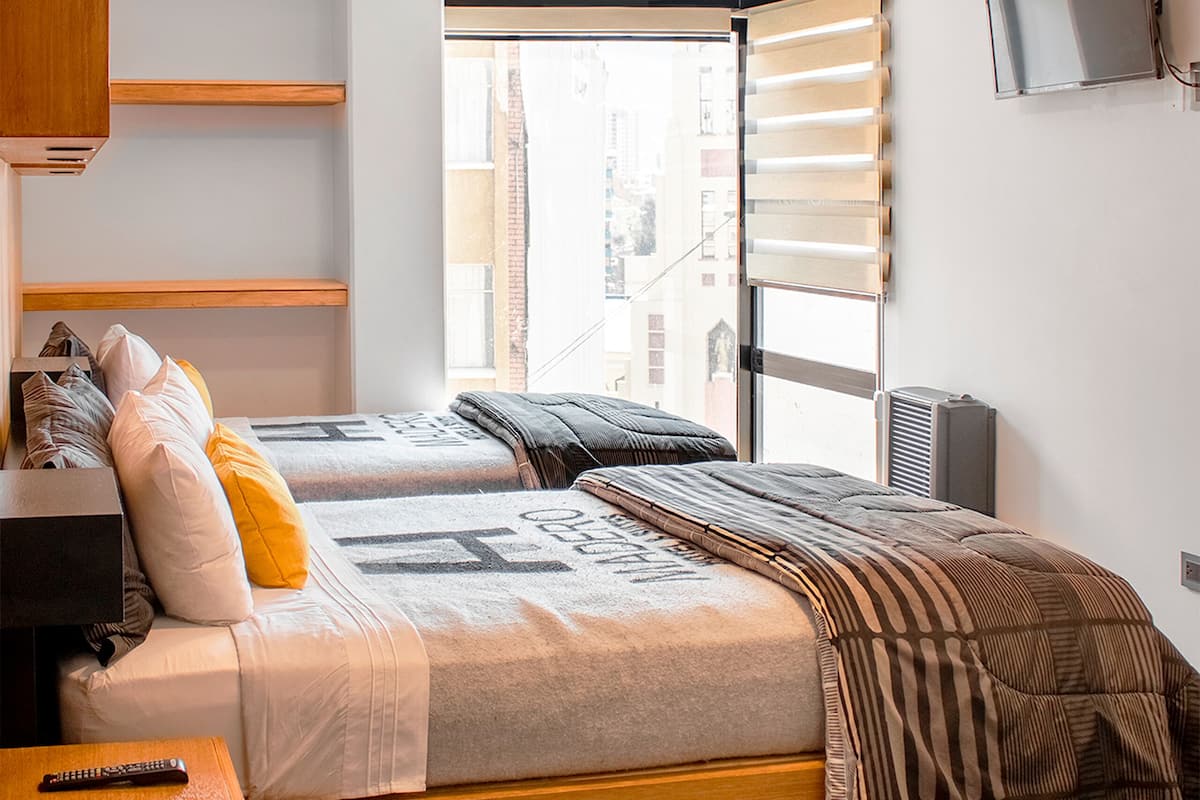 A modern bedroom with a bed, a TV, and a window.