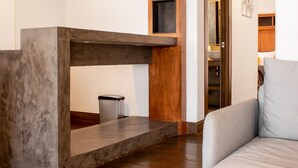 A modern living room with a built-in fireplace, a grey sofa, and a wooden ceiling structure. - Madero Hotel & Suites (La Paz)