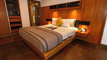 A modern hotel room with a wooden bed frame, a built-in wardrobe, and a bedside table with a lamp.