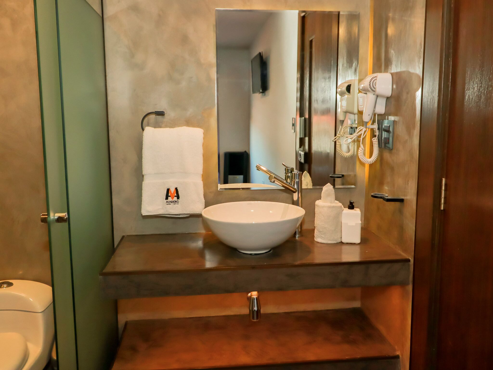 A bathroom with a white sink, a mirror, a towel, and a hairdryer.