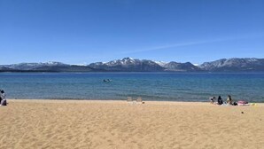 A beach with a clear sky, mountains in the background, and a few people and boats on the water. - Mountain Top View, 3 BDRs & 2 Baths, NEW HOTTUB (Stateline)