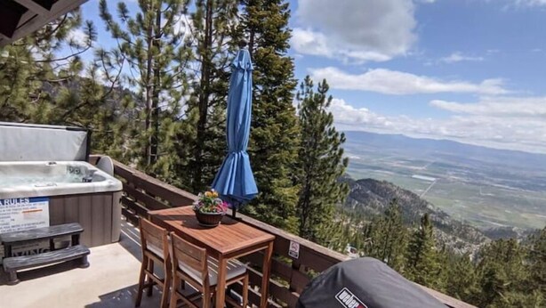 A wooden deck with a hot tub, a table with chairs, and a grill. - Mountain Top View, 3 BDRs & 2 Baths, NEW HOTTUB (Stateline)