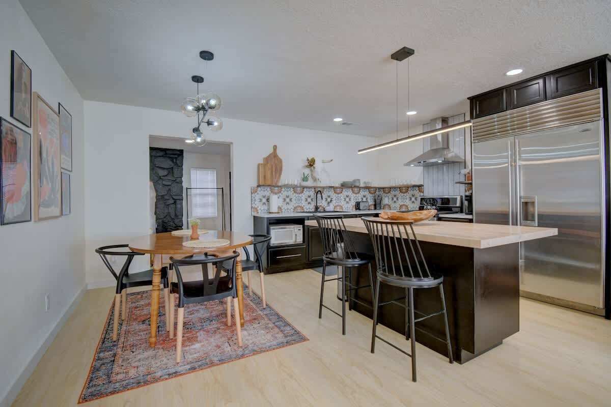 A modern kitchen with a central island, bar stools, and a large refrigerator.