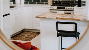 Een moderne keuken met witte kasten, een zwart betegelde spatwand en een houten eiland.