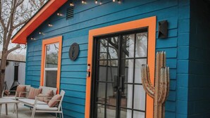 Een blauw huis met oranje details, een schuifdeur en een cactus erbij.