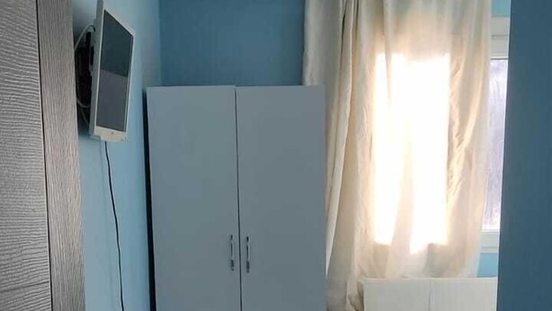 Un dormitorio pequeño y bien iluminado, con una cama, un escritorio y una silla.
