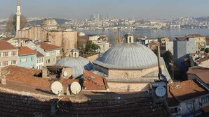 Un paisaje urbano con edificios históricos, incluyendo una cúpula destacada y un minarete, que da vista a una masa de agua.