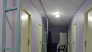 Un pasillo estrecho con suelo de madera clara y puertas a ambos lados.