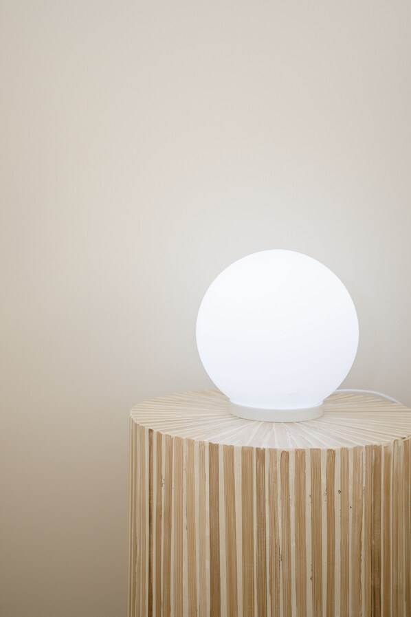 A round, illuminated object on a cylindrical wooden stand against a plain wall. - Liiiving in Porto-Uptown Pearl Apartment (Porto)
