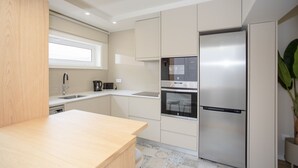 A modern kitchen with a built-in oven, a stainless steel refrigerator, and a window above the sink. - Liiiving in Porto-Uptown Pearl Apartment (Porto)