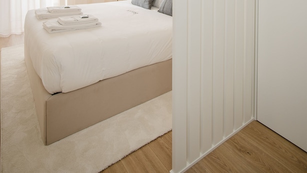A modern bedroom with a large bed, a bedside table, a lamp, and a wardrobe. - Liiiving in Porto-Uptown Pearl Apartment (Porto)