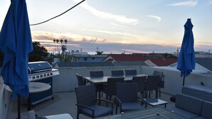 Une terrasse extérieure équipée d’un barbecue, de sièges et de parasols.