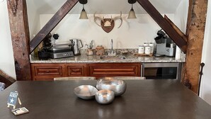 Un coin repas rustique avec une table en bois foncé, deux chaises en bois et une cuisine en arrière-plan.
