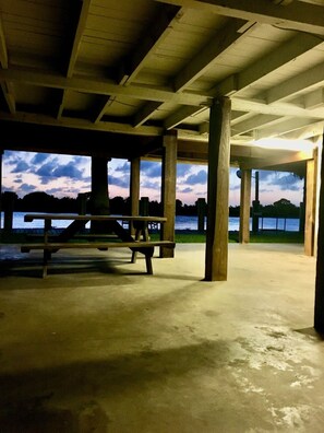Et tomt parkeringsområde under tag med støttepiller i beton og et picnicbord.