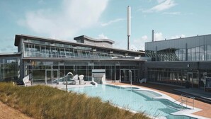 A modern building with a swimming pool and outdoor seating area. - Ferienwohnung Dünenzauber (St.Peter Ording)