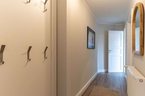 A hallway with a white door at the end, a framed picture on the wall, and a radiator on the right.