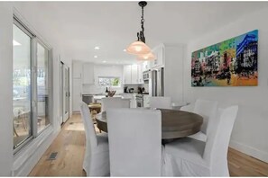 Enjoy meals around a central round table in this stylish dining area, featuring a vibrant abstract painting and modern kitchen.