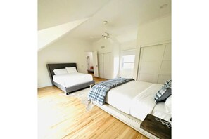 Cozy retreat with two beds, a ceiling fan, and a door leading to another room.