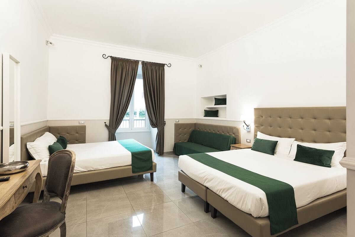 A hotel room with two beds, a desk, and a chair.