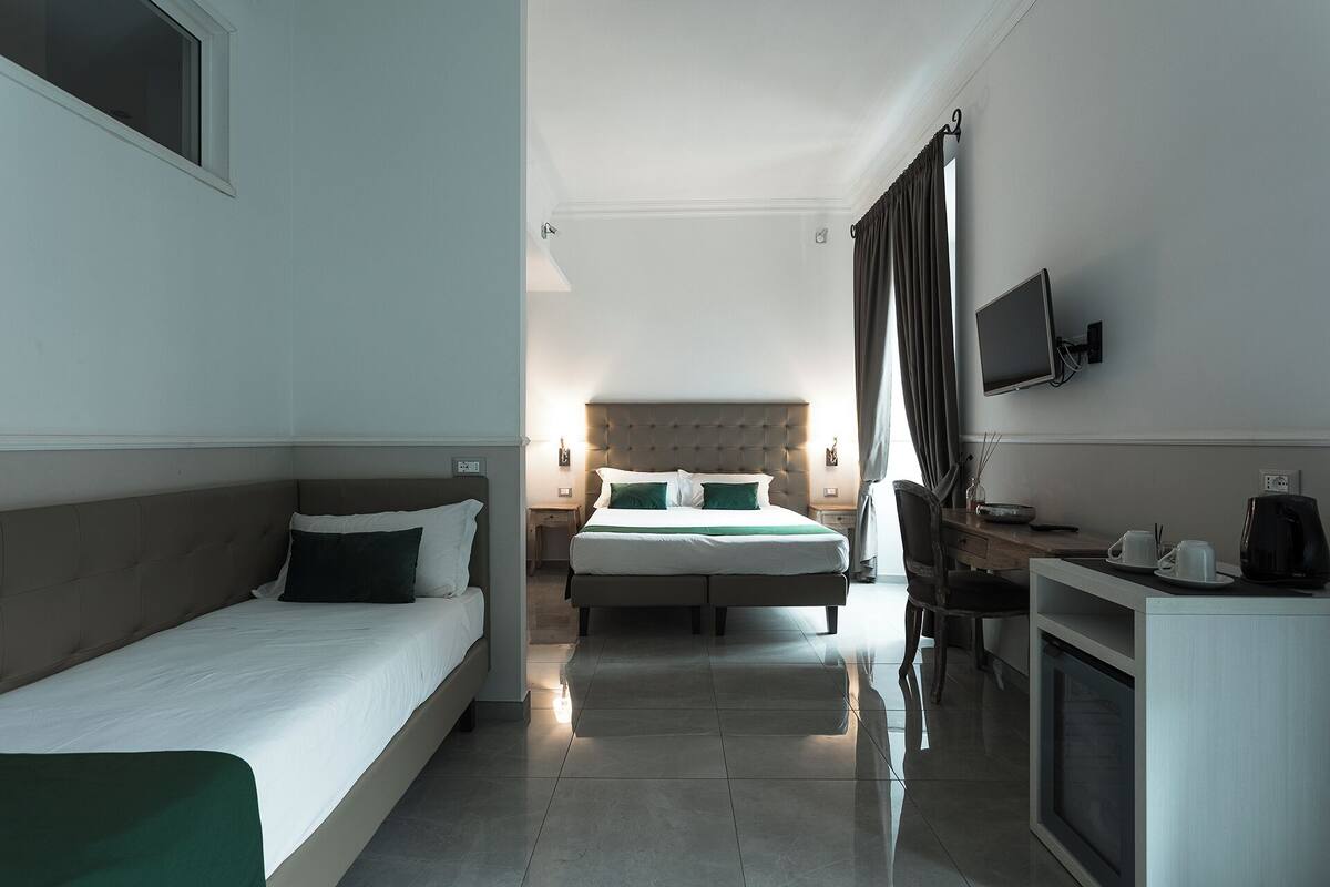 A hotel room with two beds, a TV, a desk, and a chair.
