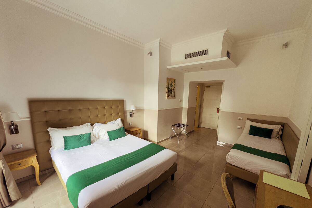 A hotel room with a large bed, a smaller bed, a desk, and a chair.