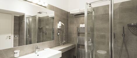 A modern bathroom with a glass-enclosed shower, a vanity with a sink, and a mirror with lights above it.