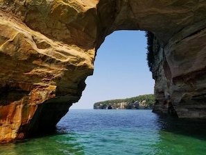 A natural rock formation with a clear view of the sea and distant land. - Private hot tub -2 king beds -near Pictured Rocks! (Christmas)