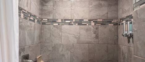 A shower with a wooden ceiling, tiled walls, and a hand shower.