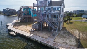 A multi-story waterfront property with a dock, multiple decks, and a sign indicating 'Ultra Sound' services.