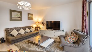 A modern living room with a sofa, coffee table, and TV. - Le Bonnet Rouge - Appartement 2 chambres avec parking (Rennes)