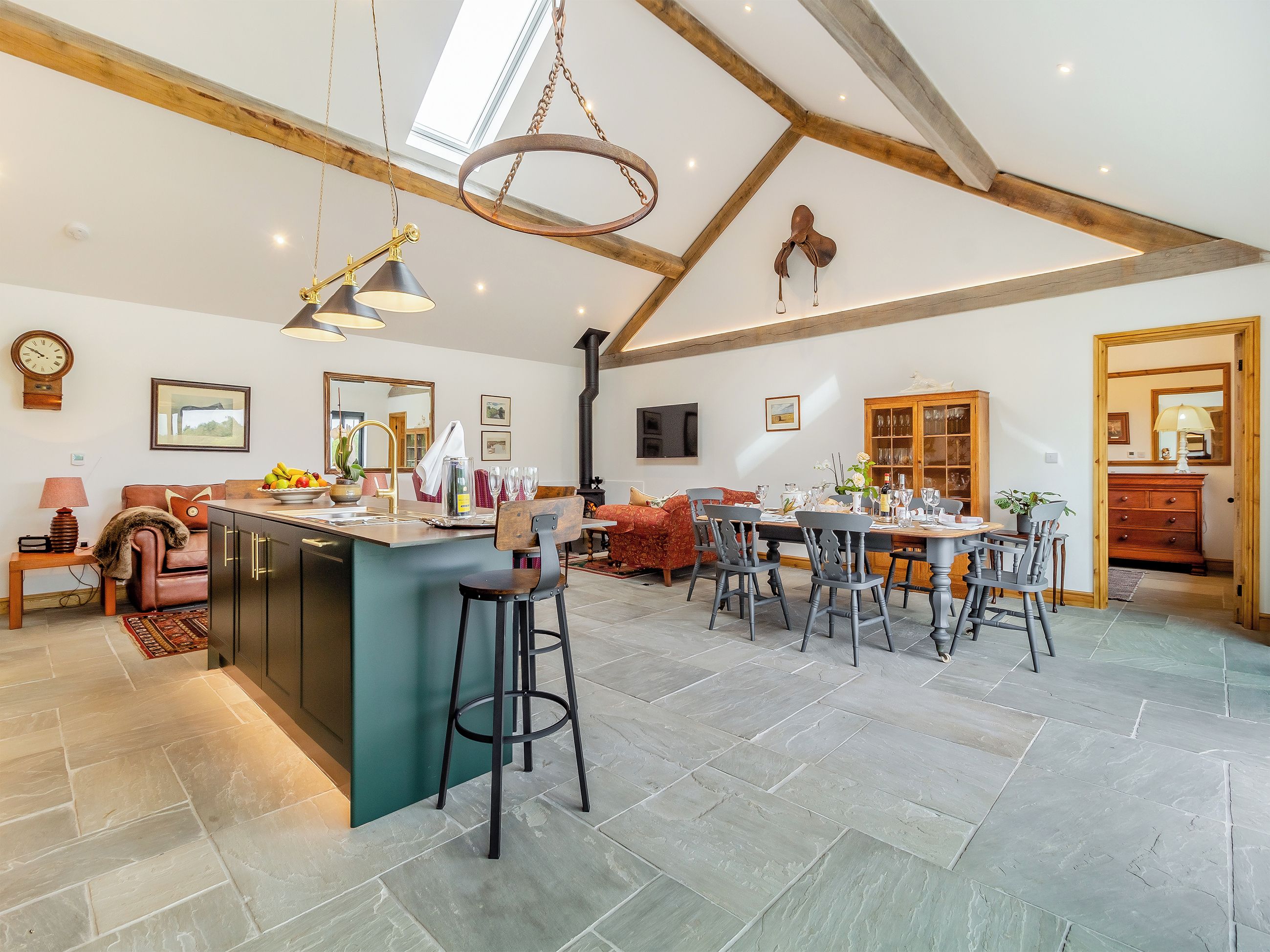 Una cocina amplia con una isla central, una zona de comedor con una mesa y sillas de madera, y una acogedora sala de estar con sofá y sillones.