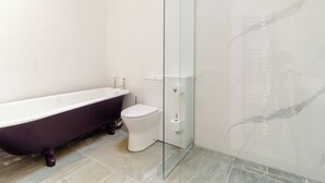 A bathroom with a freestanding bathtub, a toilet, and a glass-enclosed shower.