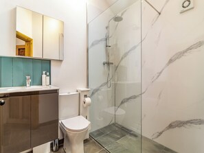 A modern bathroom with a glass-enclosed shower, a toilet, and a vanity with a mirror and countertop. - 3 bedroom accommodation in Watton (Watton)