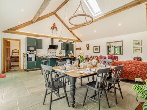 Un coin repas avec une table en bois, des chaises et une cuisine en arrière-plan.