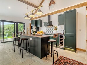 Une cuisine moderne dotée d’un îlot central, de tabourets de bar et offrant une vue sur l’extérieur.