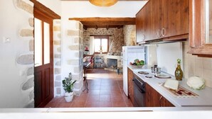A kitchen with wooden cabinets, a stone wall, and a tiled floor. - Rural Stone Villa with private pool and mountain views near local sandy beaches! (Paleloni)