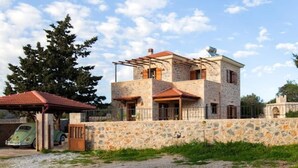 A two-story stone house with a covered porch and a car parked in front. - Rural Stone Villa with private pool and mountain views near local sandy beaches! (Paleloni)