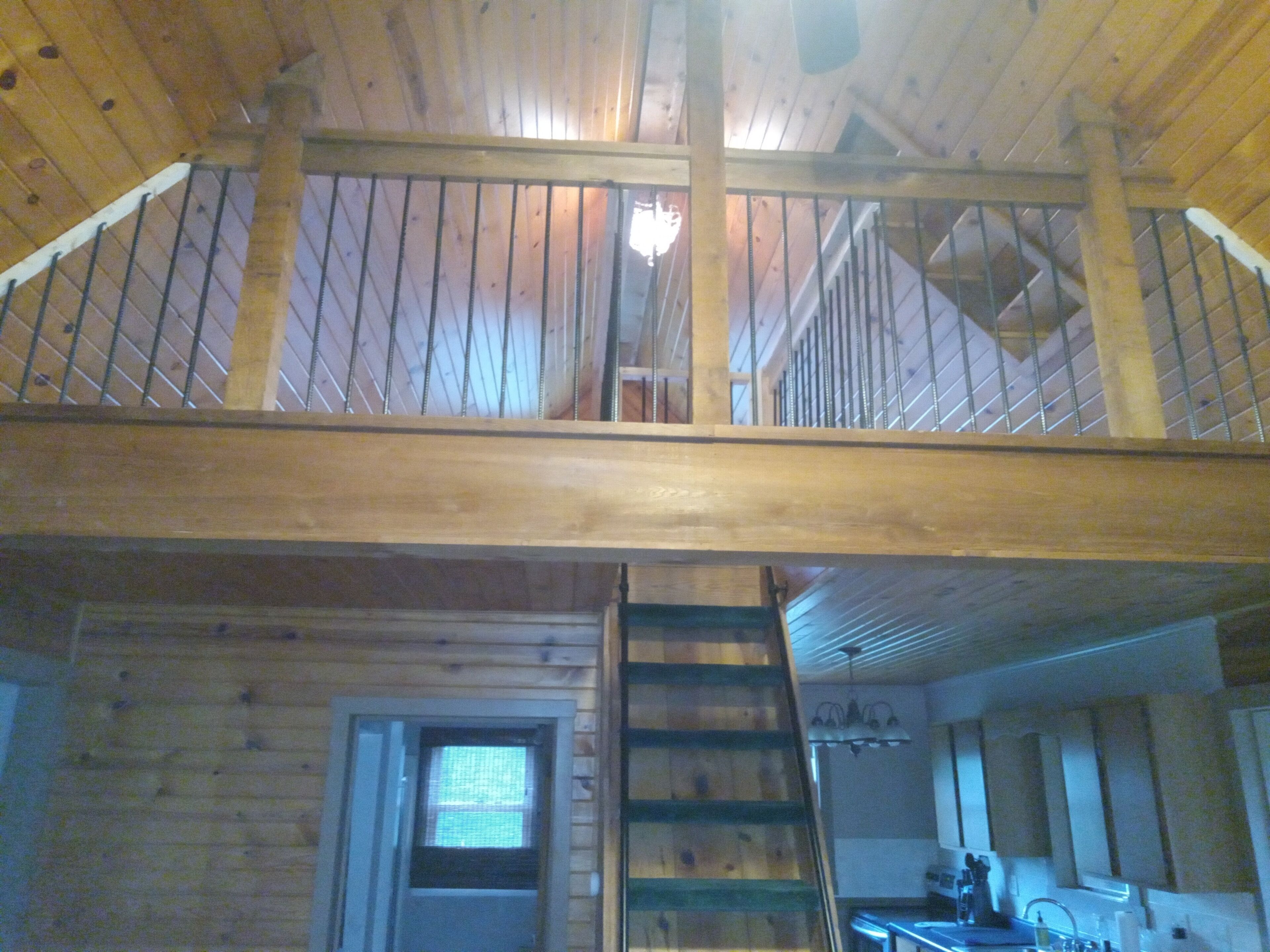 Ein Holzblock-Interieur mit Schlafzimmer auf dem Zwischenstock, einer Küchenzeile und einer Treppe.