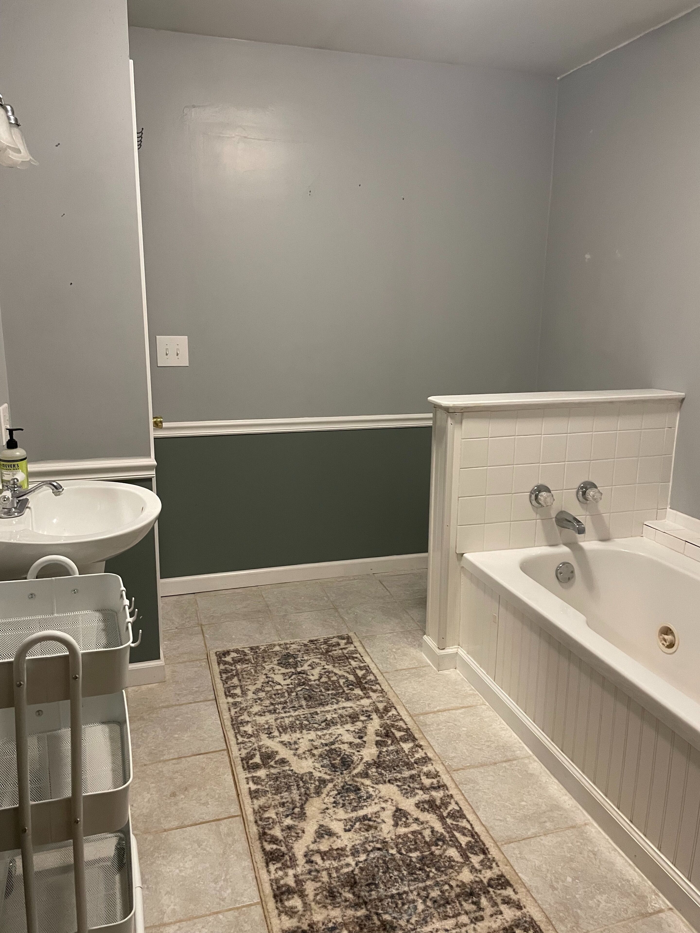 Une salle de bain avec un lavabo, une baignoire et un tapis à motifs.