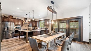 A spacious kitchen with a large island, modern appliances, and a dining area with chairs. - Trax N Trailz Lodge, Home Theatre, EV Charger, Hot Tub, Trail & Clubhouse Access (South Lawrence)