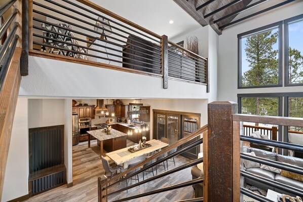 Una cocina amplia con electrodomésticos modernos, un comedor con mesa de madera y un gran ventanal con vistas a árboles.
