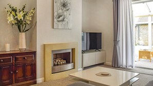 A modern living room with a fireplace, a flat-screen TV, and a large window with curtains. - A spacious and well presented bungalow with amazing views over Berkshire. (Reading)