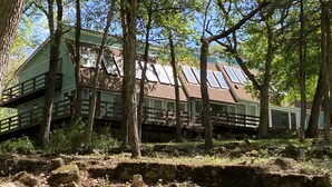 Un chalet rustique doté d’un toit en pente, d’une terrasse en bois et de nombreuses fenêtres.